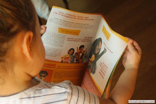 Menina lendo livro em projeto cultural realizado pela Água Grande